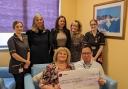 Fundraiser Carol Collier presents the donation to NHS Foundation Trust Consultant Stephen Goh along with Breast Care team members Marie Rosella and Nikita Copestake, event co-organiser Christine Brown, Jen Woolmer from Holiday Inn and Colleen Gostick